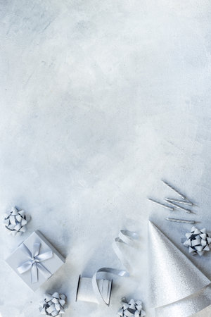 Festive party decoration in silver color with gift box and carnaval caps on gray stone background, top view.の写真素材