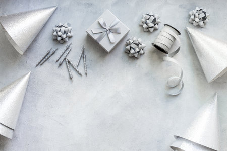 Festive party decoration in silver color with gift box and carnaval caps on gray stone background, top view.の写真素材