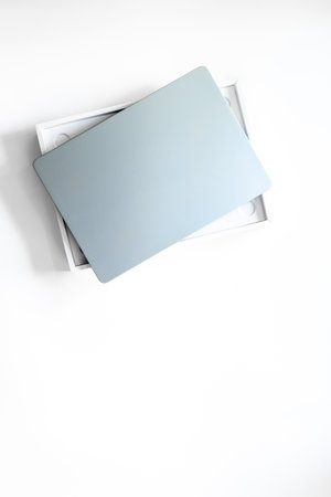 Silver laptop in a box on white desk top. Unpacking new gadget, top view.の写真素材