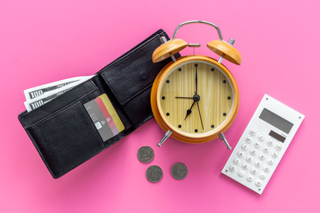 Black wallet with money cash bank card and alarm clock. Time to pay taxes or credit concept.の写真素材