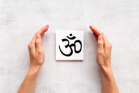 Hands holding Hinduism aum symbol.