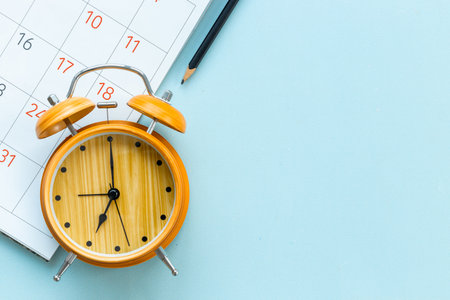 Alarm clock is on calendar with pencil, top view. Planning and time management concept.