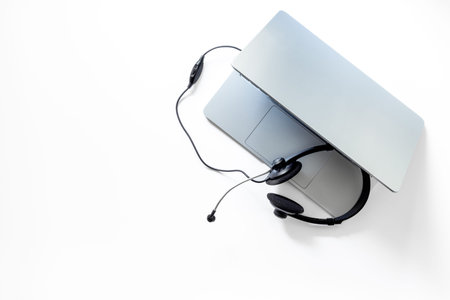 Headset and laptop - customer support equipment at call center, top view. Online conference work...