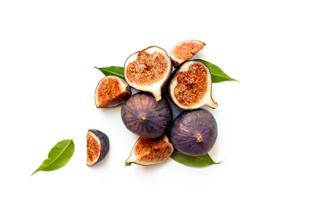 Purple ripe figs fruit and slices with green leaves top view on a white background.