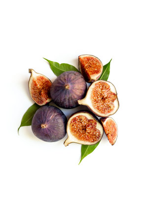 Purple ripe figs fruit and slices with green leaves top view on a white background.