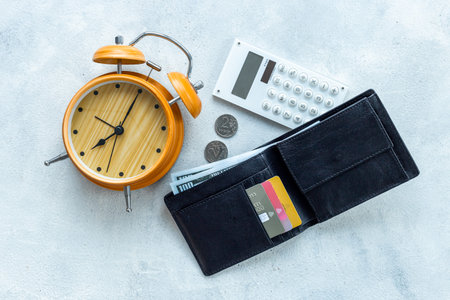 Black wallet with money cash bank card and alarm clock. Time to pay taxes or credit concept.の写真素材
