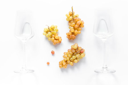Two empty wine glasses with ripe yellow grapes, top view.