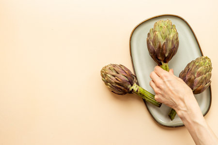 Purple artichokes flowers - edible buds on a plate top view. Vegetarian food ready to cook.の写真素材