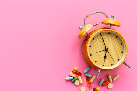 Medical treatment pills and vintage alarm clock, top view. Time to take medicine concept.の写真素材
