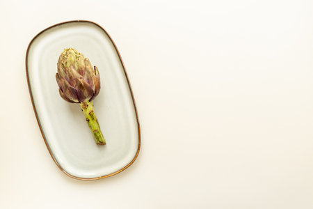 One artichoke flower on a plate top view. Vegetables food ready to cook.の写真素材