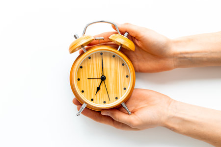 Hands are holding vintage wooden alarm clock with bells at seven o'clock. Morning routine. In time concept.の写真素材