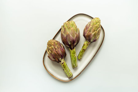 Purple artichokes flowers - edible buds on a plate top view.の写真素材