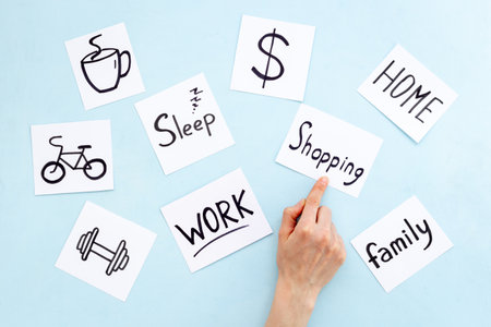 Hand is choosing Shopping word card from many paper cards with hand drawing of different life activities. Life balance conceptの写真素材