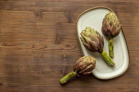 Tree heads of purple artichokes on a plate top view. Vegetables food ready to cook.の写真素材