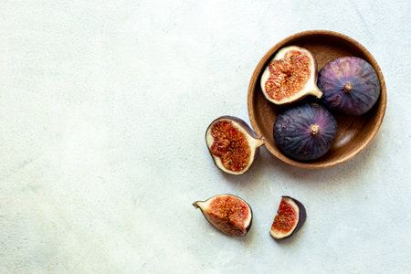 Fresh ripe figs on a wooden bowl top view on a stone background.の写真素材