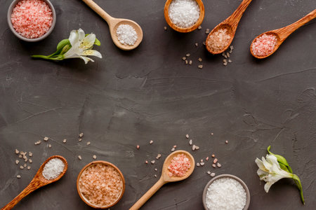 Beauty spa therapy cosmetics and wellness flat lay - sea salt in many spoons with flowers, top view.の写真素材