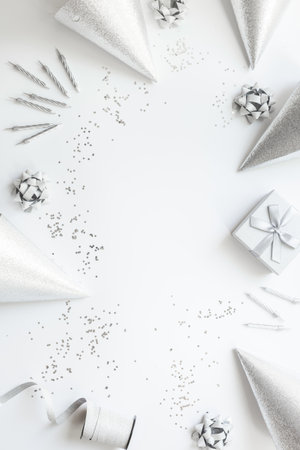 Frame of festive party decoration with silver streamers and gift box and carnaval caps on white background, top view.の写真素材