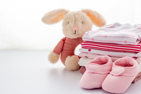 Pile of washed baby clothes with boots and toy on a table, close up.の写真素材