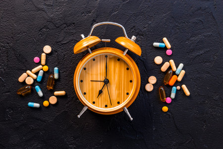Medical treatment pills and vintage alarm clock, top view. Time to take medicine concept.の写真素材