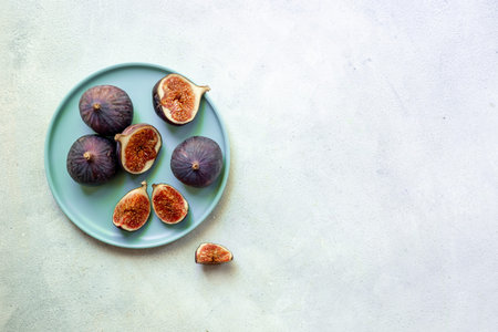 Fresh ripe figs on a plate top view on a gray background.