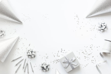 Festive party decoration in silver color with gift box and carnaval caps on white background, top view.の写真素材