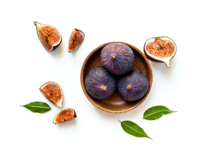 Fresh ripe figs on a wooden bowl top view on a white background.