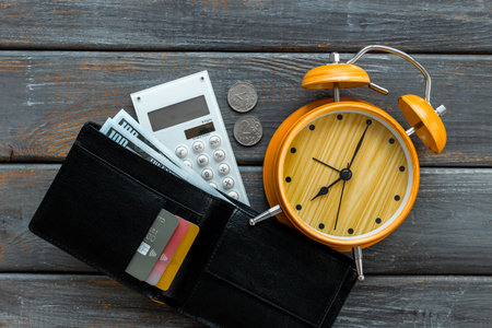 Black wallet with money cash bank card and alarm clock. Time to pay taxes or credit concept.の写真素材