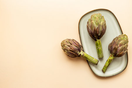 Three heads of purple artichokes on a plate top view. Vegetables ready to cook.の写真素材