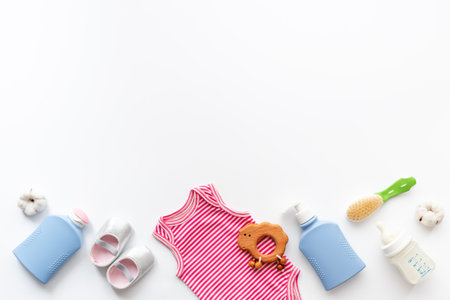 Set of baby hygiene cosmetic products - shampoo and soap with a comb. Eco friendly accessories - bodysuit and wooden toys with bottle of milk on white background, top view.の写真素材