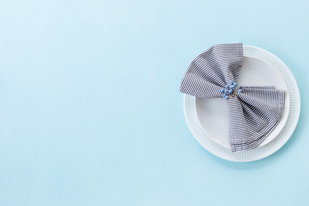 Top view of minimalistic table setting with empty plate and napkin on blue background, flat lay.の写真素材