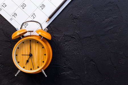 Alarm clock is on calendar with pencil, top view. Planning and time management concept.の写真素材