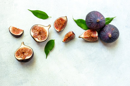 Purple ripe figs fruit and slices with green leaves top view on a stone background.の写真素材