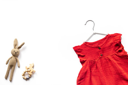Baby girl red cotton muslin dress and knitted bunny toy, top view. Kids stylish summer clothesの写真素材