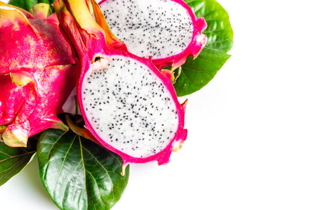 Two pitaya fruits - whole and cut in half - with green leaves on white table. Ripe dragon fruit or pitahaya. Tropical fruits, top viewの写真素材