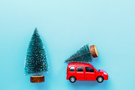 Red toy car carrying Christmas tree. Festive New Year decoration and Christmas backgroundの写真素材