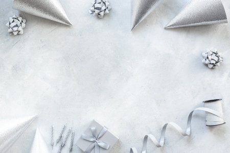 Festive party decoration in silver color with gift box and carnaval caps on gray stone background, top viewの写真素材
