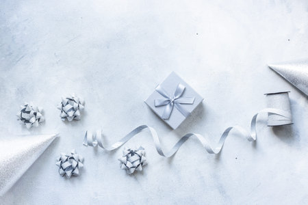 Holiday festive party flat lay with silver carnaval caps and cake candles, top view. Gift box and streamers on gray stone backgroundの写真素材