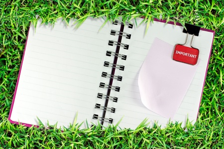 blank page of note book on grass and white isolateの写真素材