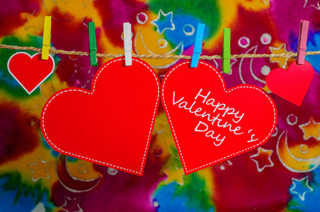 Cute big red heart hanging on the clothesline. On multicolour background