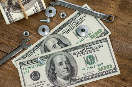 Close up bolts nuts and money on wood tableの写真素材