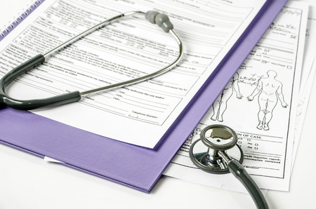 stethoscope resting on a sheet of medical lab test results, with patient file and x-ray or mri film の写真素材