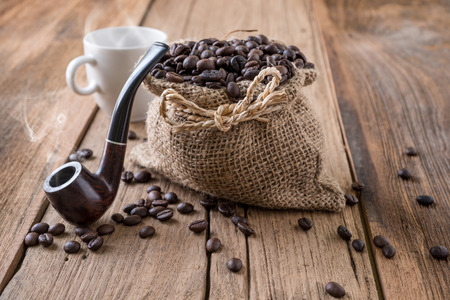coffee beans fallen out of a jute bag located on wooden tableの写真素材
