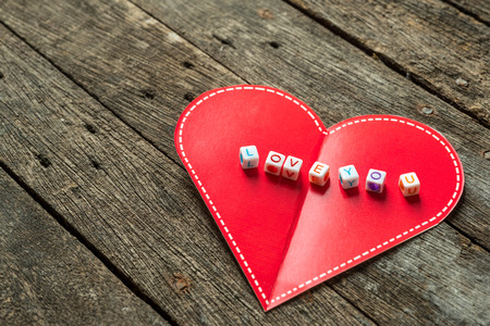 Love message written in  blocks over red heart. Wooden Backgroundの写真素材