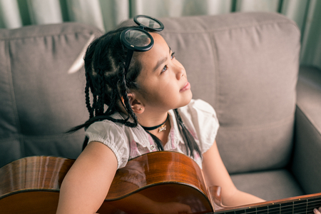 Happy smiling girl ,wearing glasses,dreadlocks hair style ,learning to play the acoustic guitarの写真素材