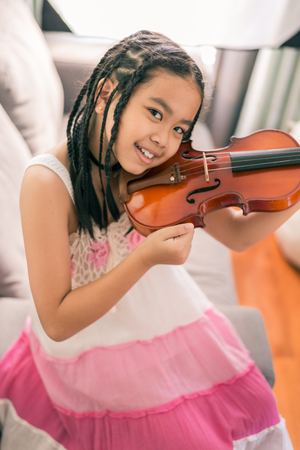 Happy smiling girl ,wearing glasses,dreadlocks hair style ,learning to play the Violinの写真素材