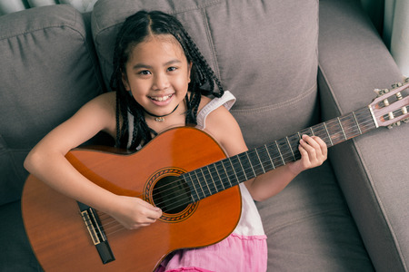 Happy smiling girl ,wearing glasses,dreadlocks hair style ,learning to play the acoustic guitarの写真素材