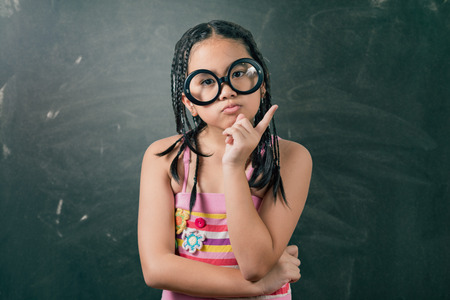 Closeup portrait of Cute little girl thinking deeply about something with hand on chinの写真素材