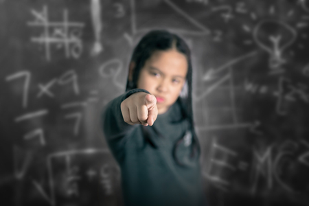 Closeup portrait of Angry Cute little asian girl pointing with her fingerの写真素材