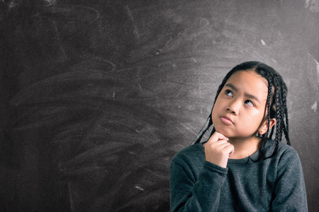 Closeup portrait of Cute little girl thinking deeply about something with hand on chinの写真素材