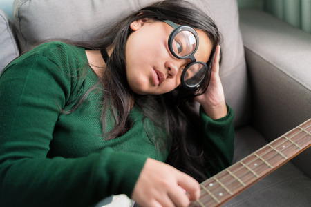 Happy smiling girl ,wearing glasses,learning to play the Bass guitarの写真素材